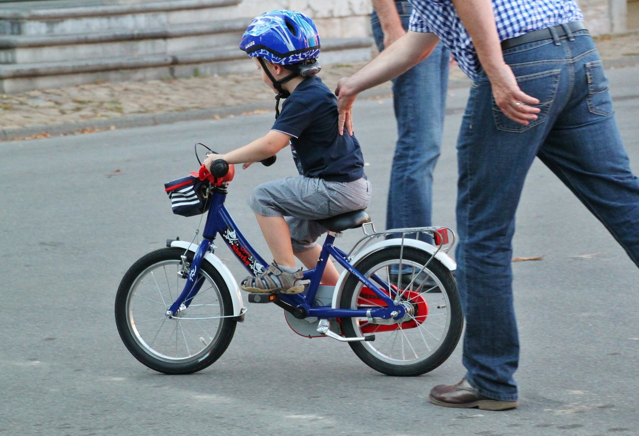 padre che insegna al figlio ad andare in bici